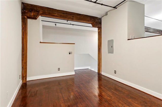 basement featuring baseboards, wood finished floors, and electric panel