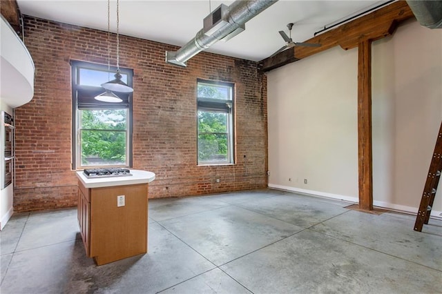 unfurnished dining area featuring brick wall, baseboards, and finished concrete floors