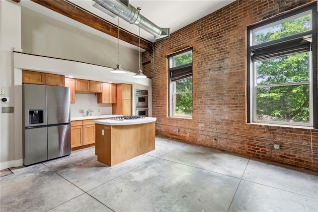 kitchen with brick wall, appliances with stainless steel finishes, a center island, concrete floors, and a high ceiling