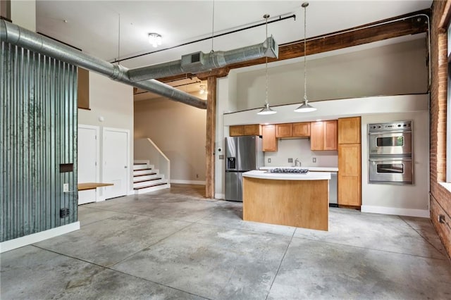 kitchen featuring baseboards, concrete floors, a kitchen island, and stainless steel appliances