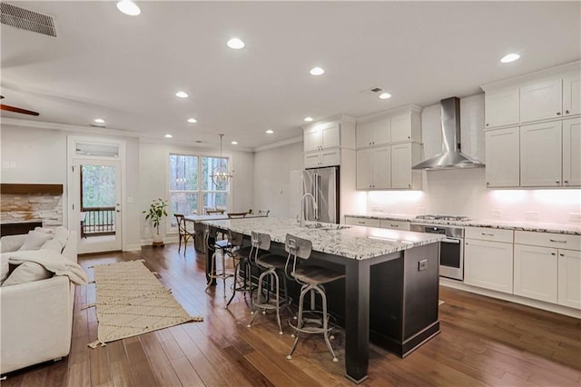 kitchen with visible vents, dark wood-type flooring, open floor plan, stainless steel appliances, and wall chimney exhaust hood