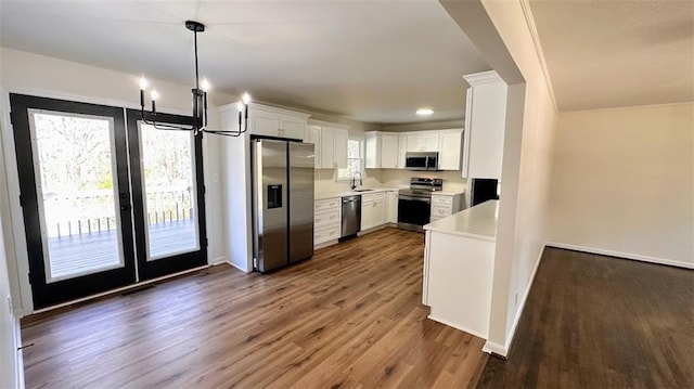 kitchen with dark wood-style floors, a sink, stainless steel appliances, light countertops, and white cabinets