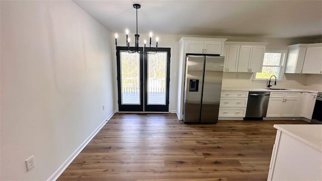 kitchen featuring an inviting chandelier, a sink, stainless steel appliances, dark wood-type flooring, and white cabinetry