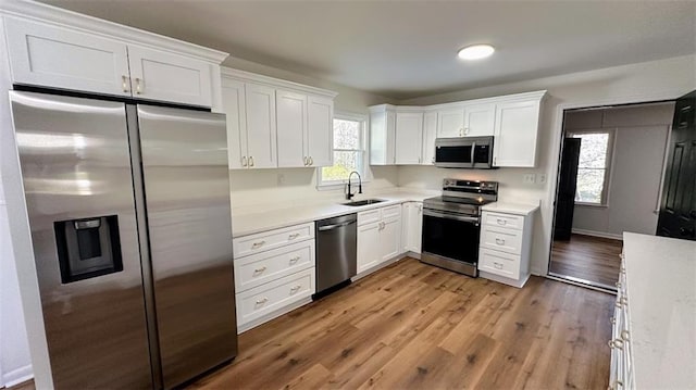 kitchen featuring a sink, stainless steel appliances, light wood-style floors, and white cabinets