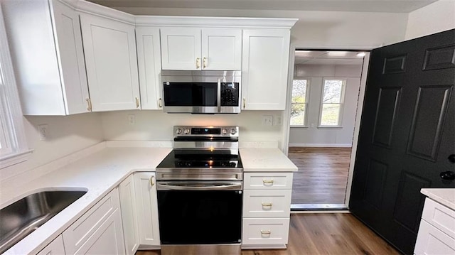 kitchen with white cabinetry, wood finished floors, appliances with stainless steel finishes, and a sink