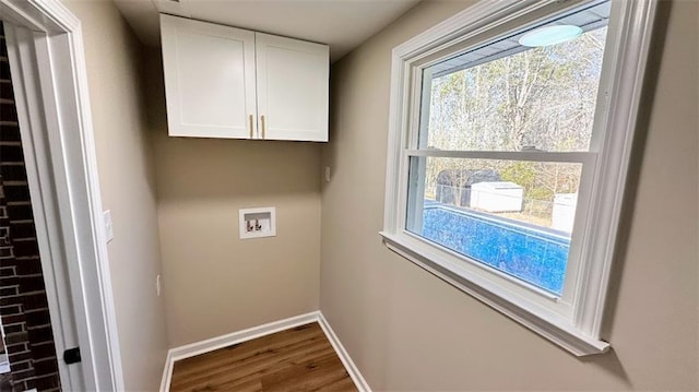 laundry area featuring cabinet space, baseboards, washer hookup, and wood finished floors