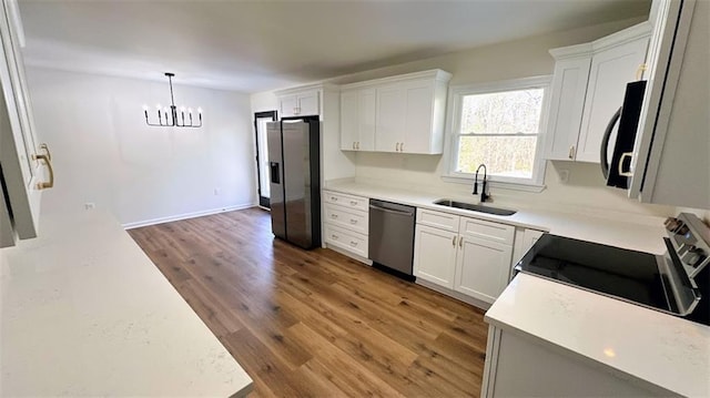 kitchen with appliances with stainless steel finishes, white cabinetry, light wood-type flooring, and a sink