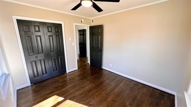 unfurnished bedroom with a ceiling fan, baseboards, dark wood-type flooring, a closet, and crown molding