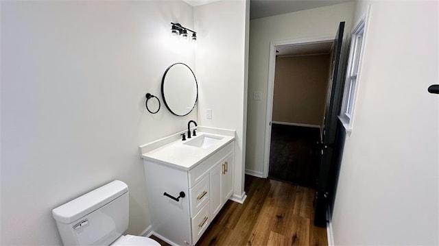 bathroom with vanity, toilet, wood finished floors, and baseboards