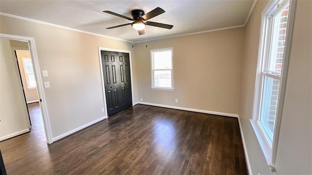 empty room with crown molding, baseboards, and dark wood-type flooring