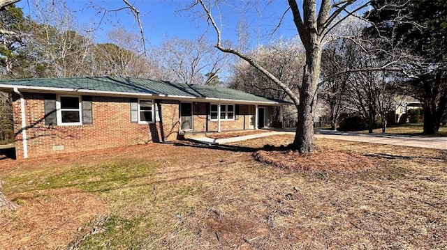 single story home featuring metal roof and brick siding