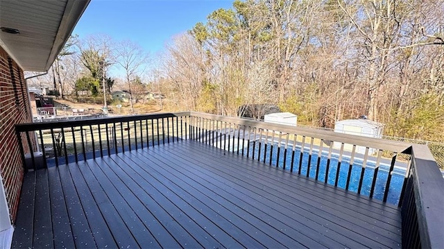 wooden deck featuring a swimming pool and an outdoor structure