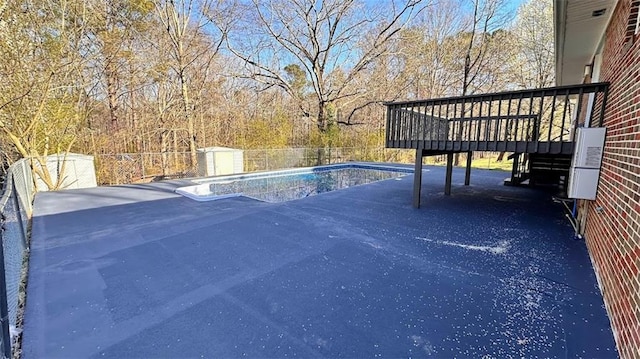 view of swimming pool featuring a patio area, a fenced in pool, a deck, and fence