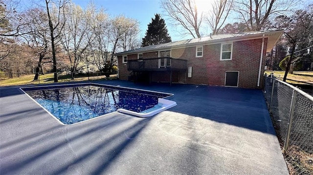 outdoor pool featuring a wooden deck, a patio, and fence