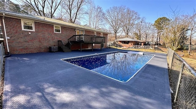 view of pool with a fenced in pool, fence, a wooden deck, central AC unit, and a patio area