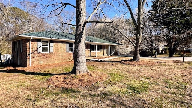 view of front facade with brick siding, crawl space, and metal roof