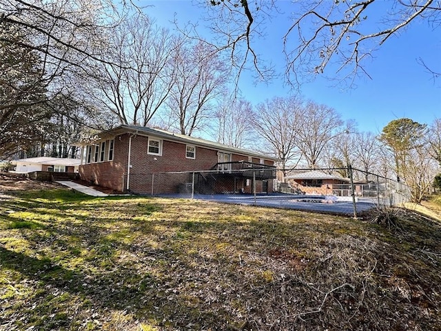 back of property featuring brick siding, a deck, and a lawn