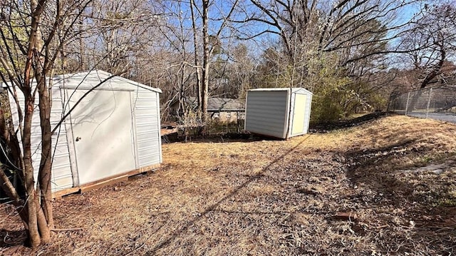 view of yard featuring a storage unit, an outdoor structure, and fence