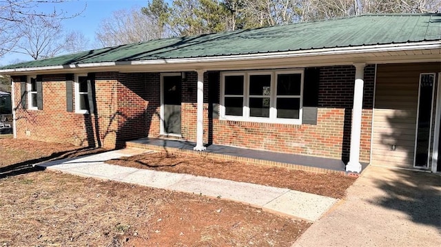 view of front facade featuring covered porch, brick siding, and metal roof