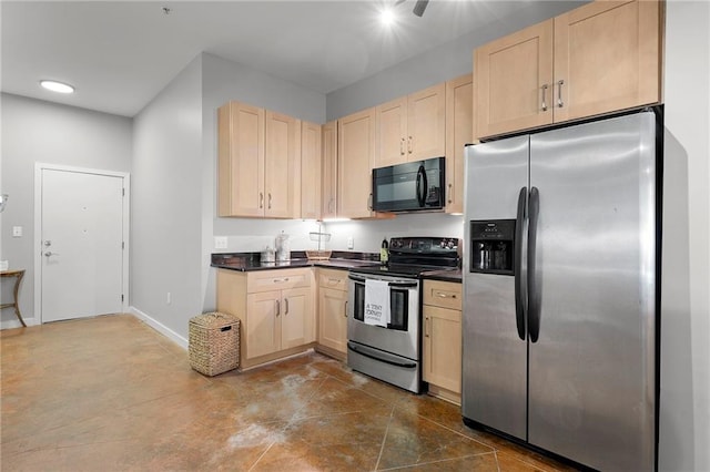 kitchen with appliances with stainless steel finishes, light brown cabinetry, dark countertops, and baseboards