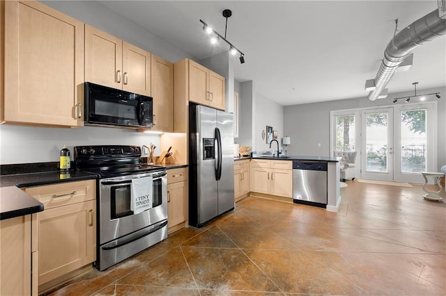 kitchen with appliances with stainless steel finishes, light brown cabinetry, a peninsula, and dark countertops