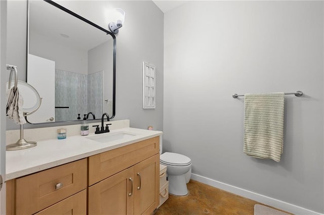 bathroom featuring baseboards, vanity, toilet, and concrete floors