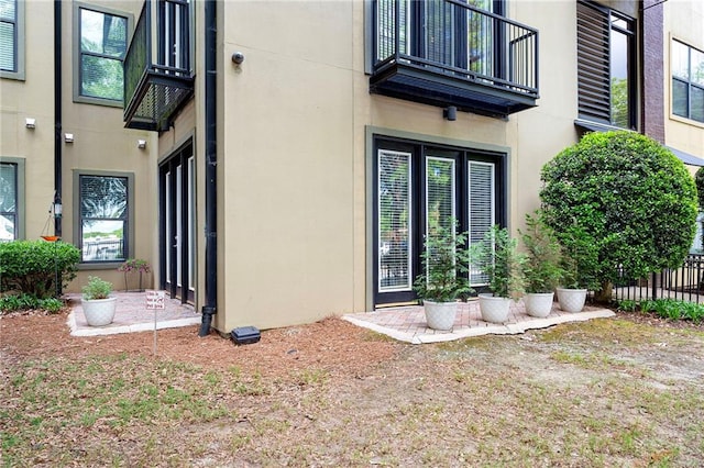 entrance to property with a balcony and stucco siding