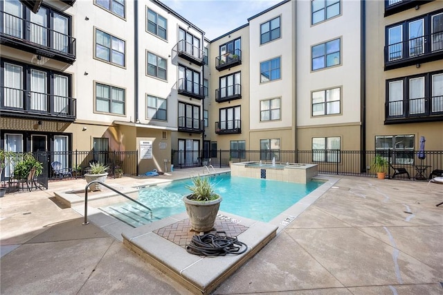 view of swimming pool with fence and a pool with connected hot tub