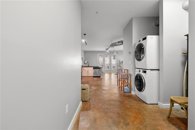 laundry room featuring stacked washer and clothes dryer and baseboards