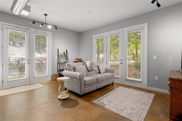 living room with healthy amount of natural light, french doors, finished concrete floors, and track lighting