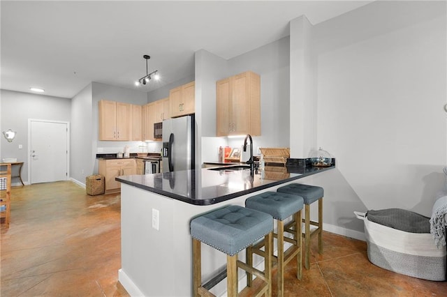 kitchen featuring stainless steel appliances, light brown cabinets, a sink, a peninsula, and a breakfast bar