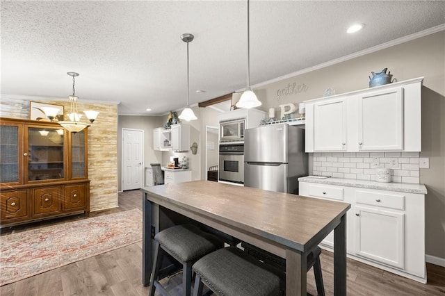 kitchen with white cabinetry, hanging light fixtures, and stainless steel appliances