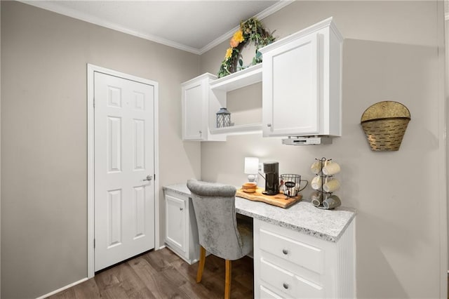 home office featuring dark wood-type flooring, built in desk, and crown molding