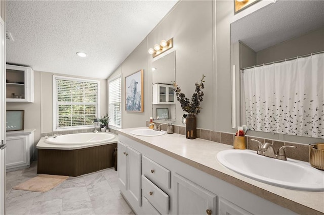 bathroom featuring vanity, a textured ceiling, a tub, and vaulted ceiling