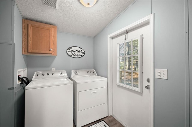 laundry area with crown molding, washer and clothes dryer, a textured ceiling, cabinets, and hardwood / wood-style flooring