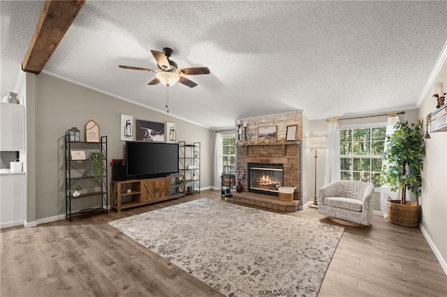 living room featuring a stone fireplace, a textured ceiling, hardwood / wood-style flooring, and ceiling fan