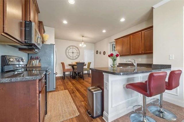 kitchen featuring electric range, stainless steel microwave, brown cabinets, a peninsula, and a sink