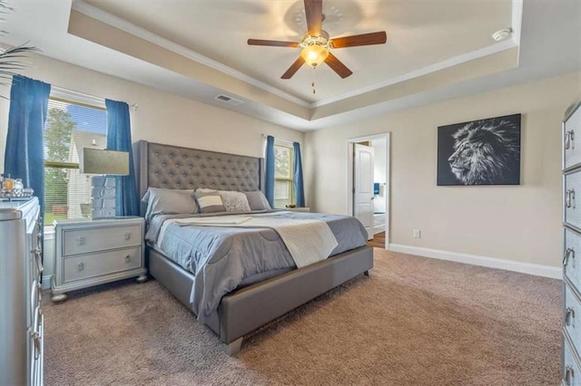 carpeted bedroom with baseboards, a tray ceiling, and ornamental molding