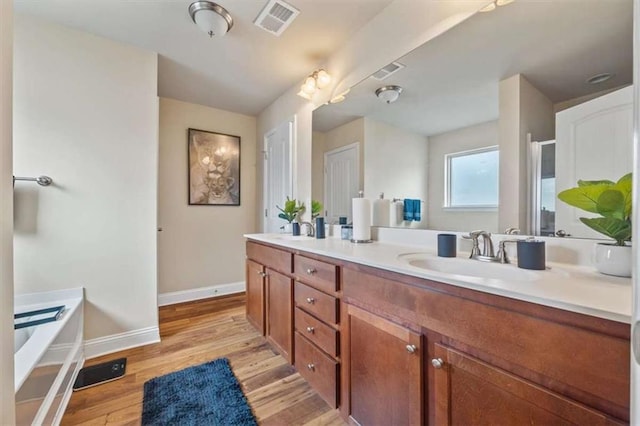 bathroom with baseboards, visible vents, a sink, and wood finished floors