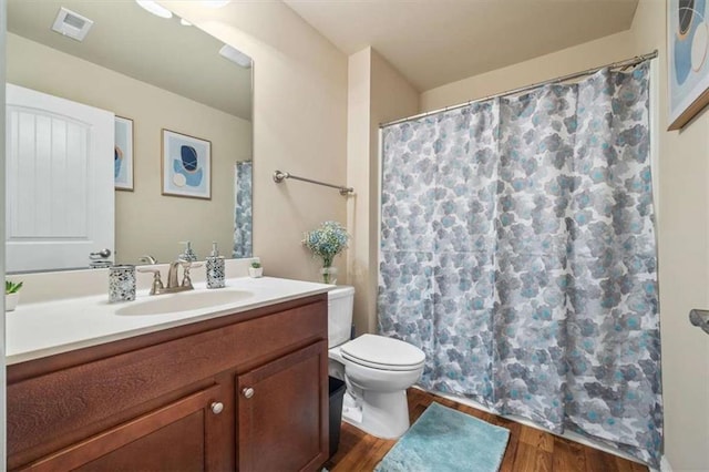 full bathroom with visible vents, toilet, wood finished floors, curtained shower, and vanity