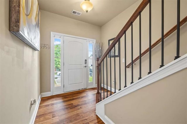 entrance foyer featuring hardwood / wood-style flooring, baseboards, stairs, and visible vents