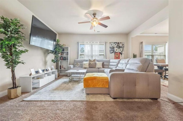 living room with carpet floors, baseboards, and a ceiling fan