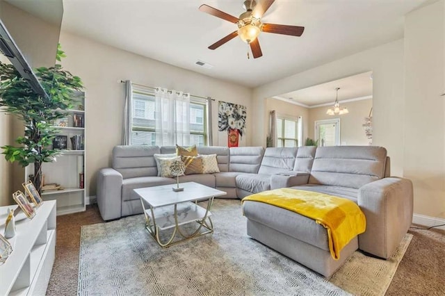 carpeted living area featuring visible vents, crown molding, baseboards, and ceiling fan with notable chandelier