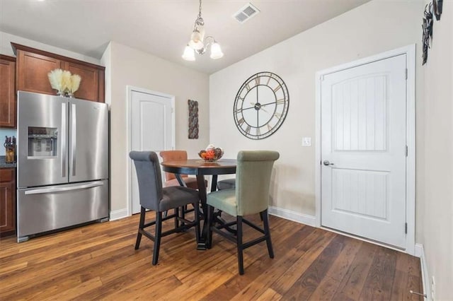 dining room featuring dark wood-style floors, baseboards, visible vents, and a notable chandelier