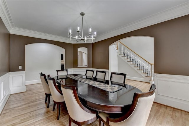 12130 Helleri Holw, Alpharetta, GA 30005 - dining space with a chandelier, arched walkways, light wood-style floors, a decorative wall, and wainscoting
