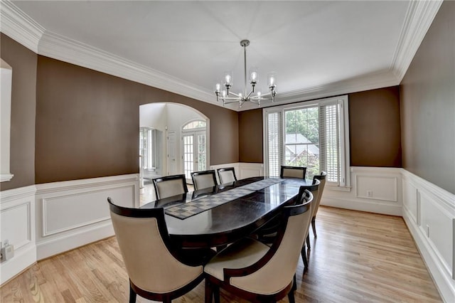 12130 Helleri Holw, Alpharetta, GA 30005 - dining area featuring arched walkways, a chandelier, light wood-style floors, crown molding, and a decorative wall