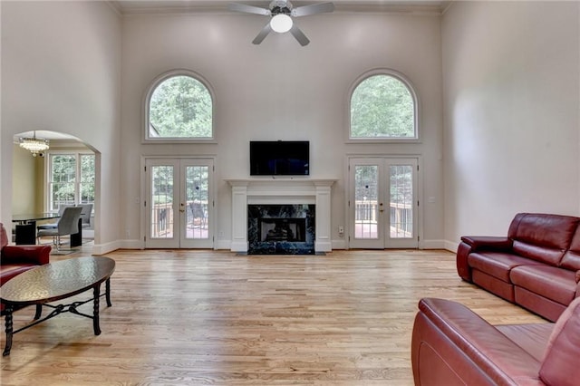 12130 Helleri Holw, Alpharetta, GA 30005 - living area with french doors, a towering ceiling, a ceiling fan, arched walkways, and light wood-style floors
