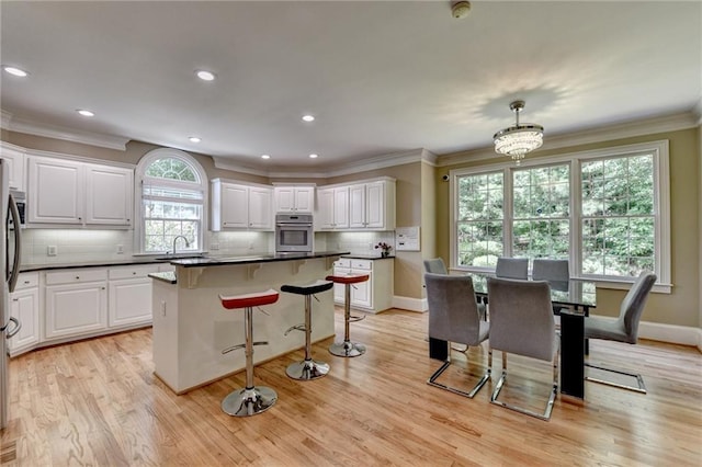 12130 Helleri Holw, Alpharetta, GA 30005 - kitchen featuring oven, white cabinetry, crown molding, decorative backsplash, and a breakfast bar