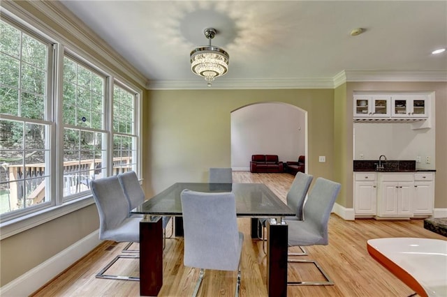 12130 Helleri Holw, Alpharetta, GA 30005 - dining space with arched walkways, plenty of natural light, wet bar, light wood-style flooring, and crown molding