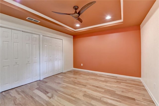 12130 Helleri Holw, Alpharetta, GA 30005 - unfurnished bedroom with a tray ceiling, multiple closets, wood finished floors, baseboards, and recessed lighting